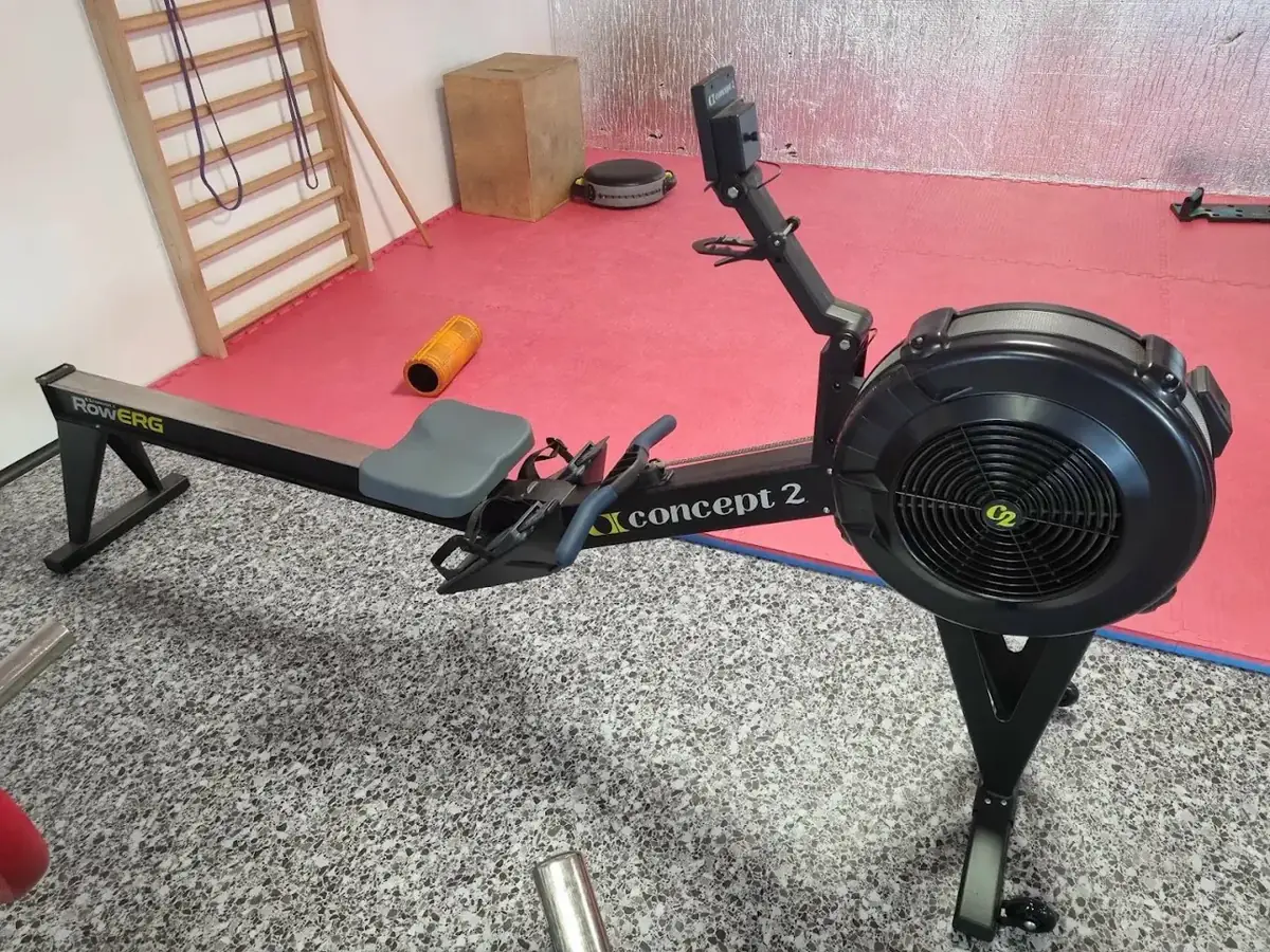 Rameur Concept2 posé sur le tapis rouge, devant l’espalier de la Salle de Musculation Gévaudan à Saugues